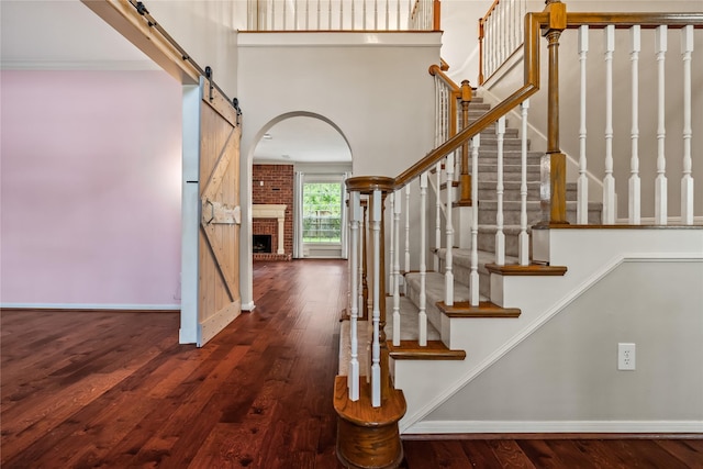 6615 Cypress Village Dr, Sugar Land, TX 77479 - staircase featuring a fireplace, a towering ceiling, wood-type flooring, and baseboards