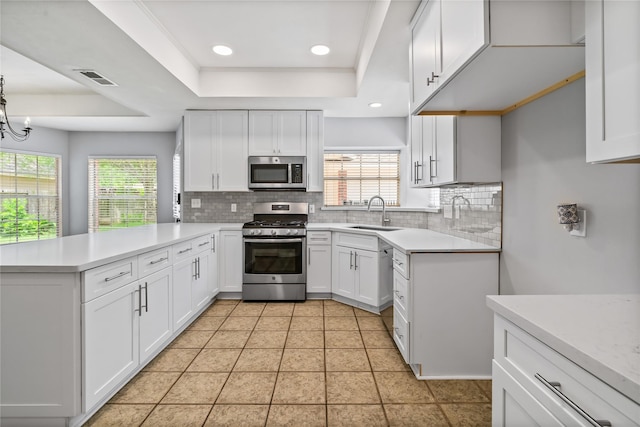 6615 Cypress Village Dr, Sugar Land, TX 77479 - kitchen with a peninsula, a sink, visible vents, appliances with stainless steel finishes, and decorative backsplash