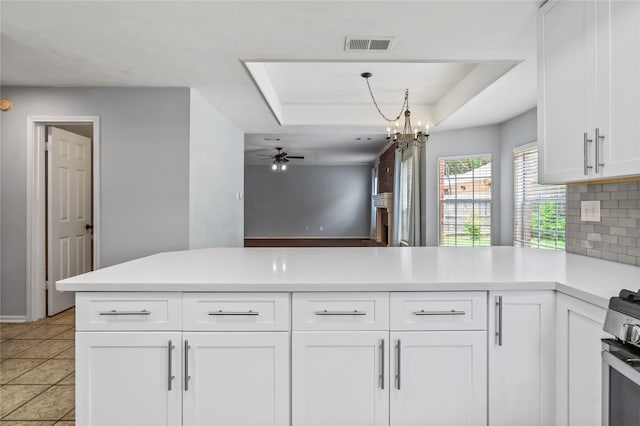 6615 Cypress Village Dr, Sugar Land, TX 77479 - kitchen with stainless steel range with gas cooktop, a peninsula, ceiling fan with notable chandelier, white cabinets, and a raised ceiling