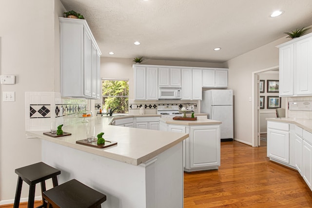 6811 S Trace Dr, Magnolia, TX 77354 - kitchen with white appliances, a peninsula, decorative backsplash, and white cabinets