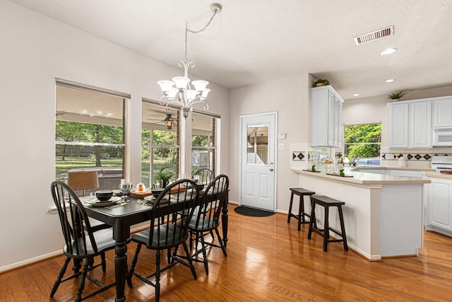 6811 S Trace Dr, Magnolia, TX 77354 - dining area featuring light wood-style flooring, ceiling fan with notable chandelier, visible vents, baseboards, and recessed lighting