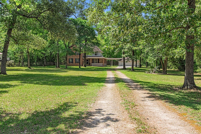 6811 S Trace Dr, Magnolia, TX 77354 - view of front of house featuring dirt driveway, fence, a carport, a front yard, and brick siding