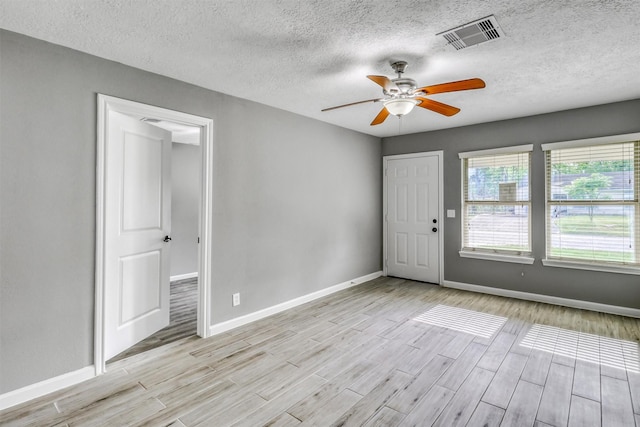 empty room with light wood-type flooring, ceiling fan, baseboards, and visible vents