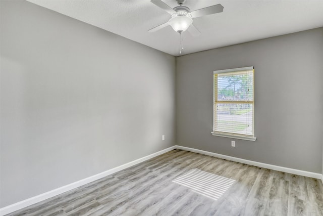 empty room featuring baseboards, ceiling fan, and light wood-type flooring