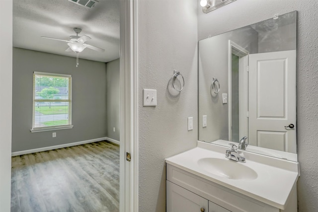 bathroom featuring wood finished floors, vanity, visible vents, ceiling fan, and baseboards