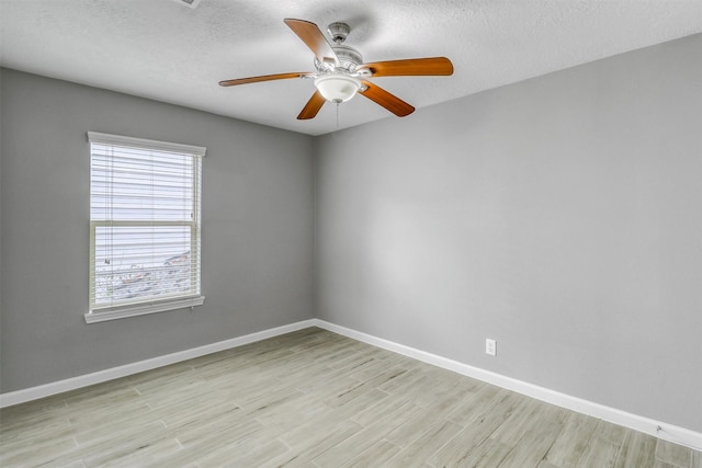 spare room featuring ceiling fan, light wood-style flooring, and baseboards