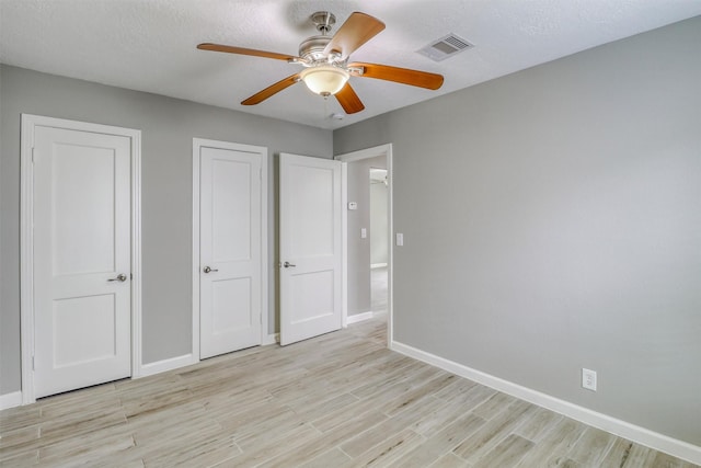 unfurnished bedroom featuring baseboards, ceiling fan, light wood-style flooring, and visible vents