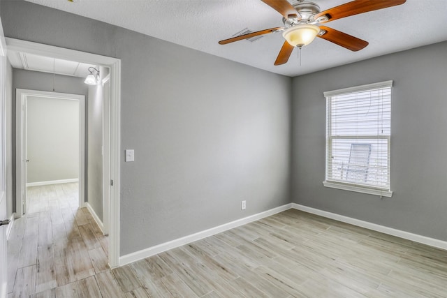 unfurnished room with attic access, baseboards, a ceiling fan, and wood finished floors
