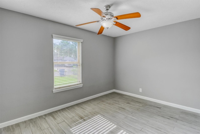 spare room featuring light wood-style flooring, baseboards, and a ceiling fan