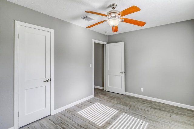 unfurnished bedroom with baseboards, ceiling fan, visible vents, and wood finished floors