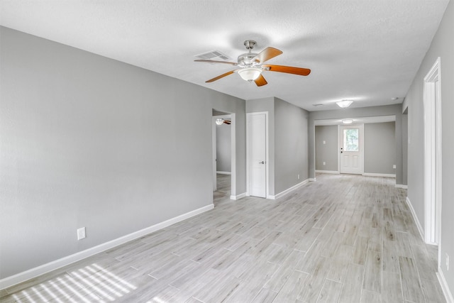 unfurnished room featuring baseboards, light wood-style flooring, ceiling fan, and a textured ceiling