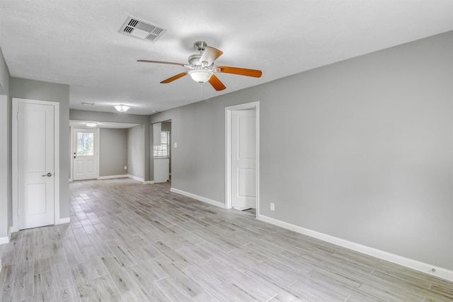unfurnished room with ceiling fan, baseboards, visible vents, and light wood-style floors