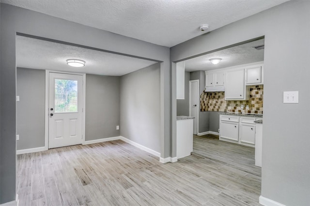 foyer featuring a textured ceiling, baseboards, and light wood-style flooring