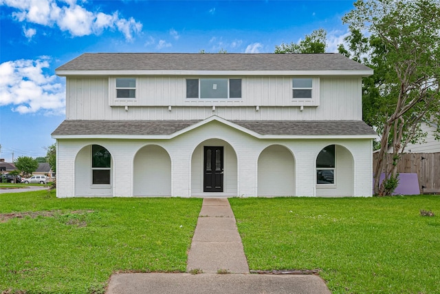 traditional home with a shingled roof and a front lawn
