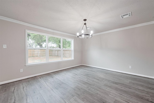 empty room with a textured ceiling, a chandelier, wood finished floors, and visible vents