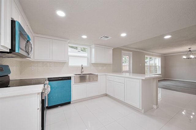 kitchen with a sink, a peninsula, stainless steel appliances, visible vents, and white cabinetry