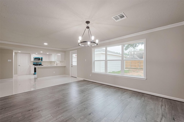 unfurnished living room featuring an inviting chandelier, visible vents, wood finished floors, and ornamental molding