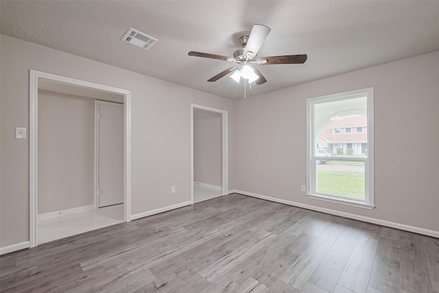 unfurnished bedroom with baseboards, visible vents, a textured ceiling, and wood finished floors