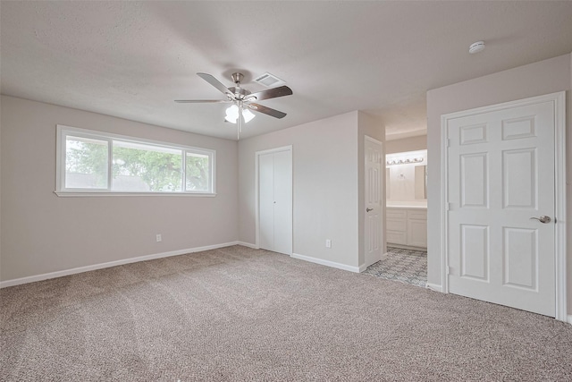 unfurnished bedroom with baseboards, ensuite bathroom, carpet flooring, and a ceiling fan