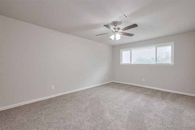 carpeted empty room with baseboards, a ceiling fan, and visible vents