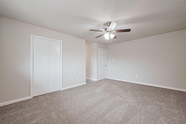 unfurnished bedroom with carpet flooring, baseboards, a ceiling fan, and a closet