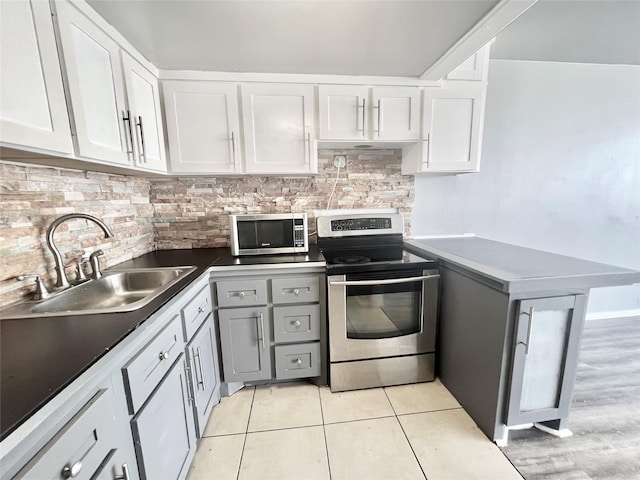 kitchen featuring a sink, white cabinets, appliances with stainless steel finishes, tasteful backsplash, and light tile patterned flooring