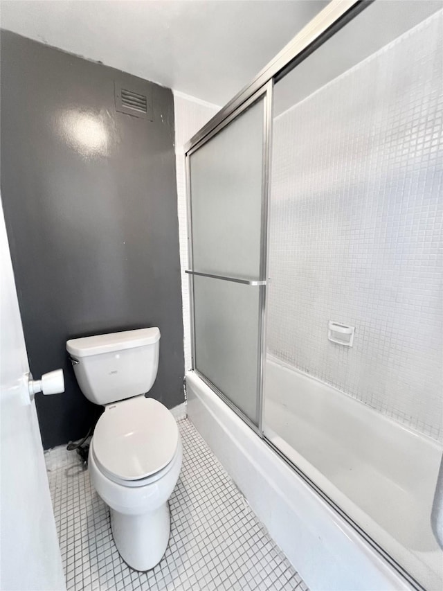 bathroom featuring toilet, tile patterned flooring, visible vents, and shower / bath combination with glass door