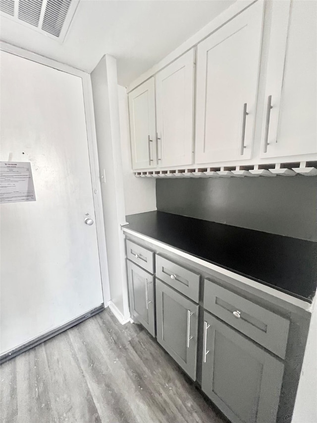 kitchen with light wood-style flooring, visible vents, gray cabinetry, and white cabinets
