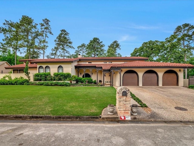 mediterranean / spanish-style home with an attached garage, concrete driveway, stucco siding, and a front yard