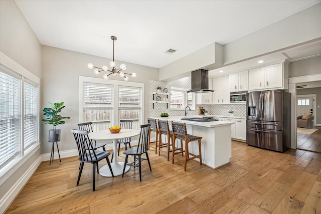1411 Tulane St, Houston, TX 77008 - kitchen with appliances with stainless steel finishes, wall chimney range hood, a chandelier, light wood-style floors, and backsplash