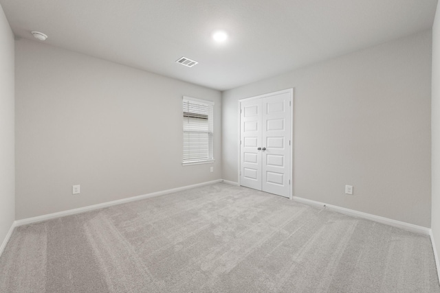 unfurnished bedroom featuring baseboards, a closet, visible vents, and light colored carpet