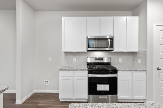 kitchen with dark wood-style flooring, stainless steel appliances, baseboards, and white cabinets