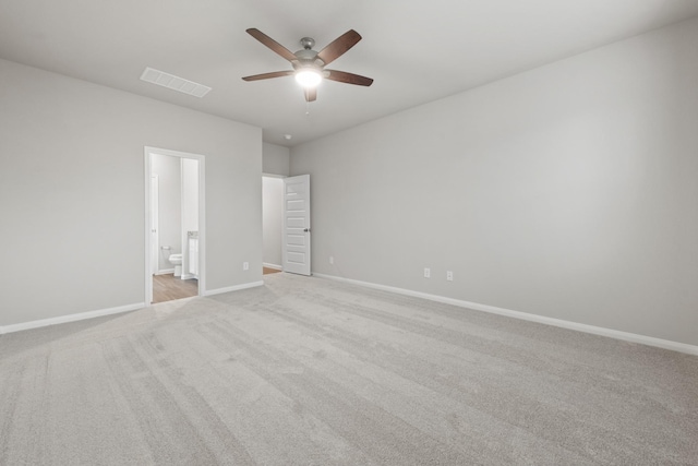 unfurnished bedroom featuring baseboards, ensuite bath, ceiling fan, visible vents, and light carpet