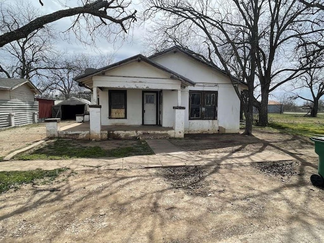 bungalow featuring a porch and stucco siding