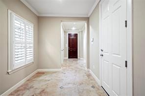 hall featuring baseboards, crown molding, and plenty of natural light