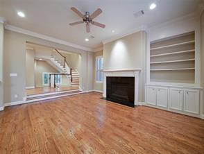 unfurnished living room with ornamental molding, stairs, a ceiling fan, and wood finished floors