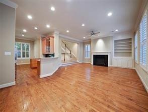 unfurnished living room featuring crown molding, baseboards, a fireplace, and recessed lighting