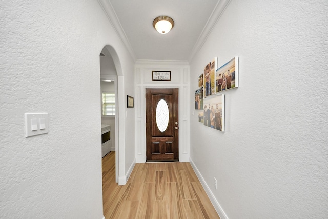 11202 Leah Elizabeth Dr, Needville, TX 77461 - doorway to outside featuring arched walkways, ornamental molding, a textured wall, light wood finished floors, and baseboards