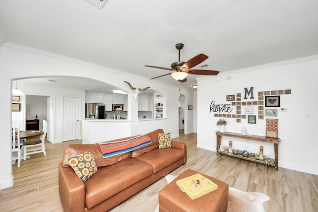 11202 Leah Elizabeth Dr, Needville, TX 77461 - living area featuring arched walkways, ornamental molding, ceiling fan, light wood-style flooring, and baseboards