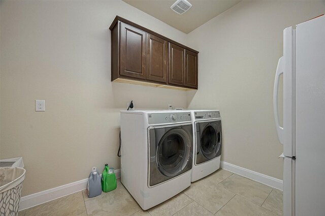17019 Mahogany Trace Ln, Richmond, TX 77407 - clothes washing area with light tile patterned floors, cabinet space, washing machine and clothes dryer, visible vents, and baseboards