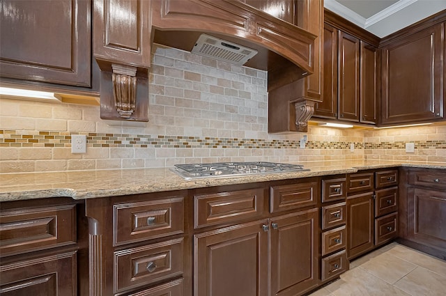 17019 Mahogany Trace Ln, Richmond, TX 77407 - kitchen featuring stainless steel gas stovetop, crown molding, decorative backsplash, light tile patterned floors, and light stone countertops