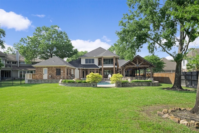 rear view of house with a fenced backyard, a fenced in pool, a yard, and brick siding