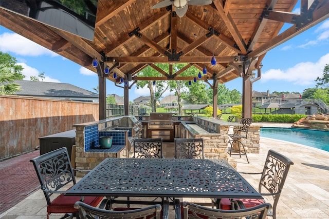 view of patio with fence, a grill, ceiling fan, exterior bar, and a gazebo