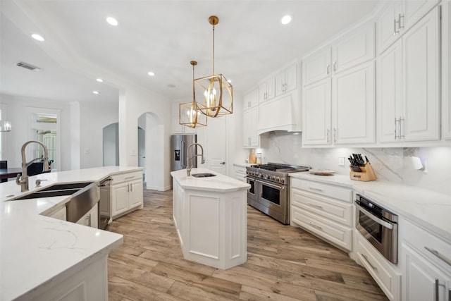 kitchen featuring a spacious island, visible vents, custom range hood, high end appliances, and arched walkways