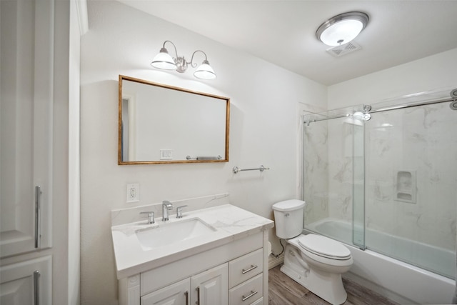 bathroom featuring toilet, wood finished floors, vanity, visible vents, and combined bath / shower with glass door