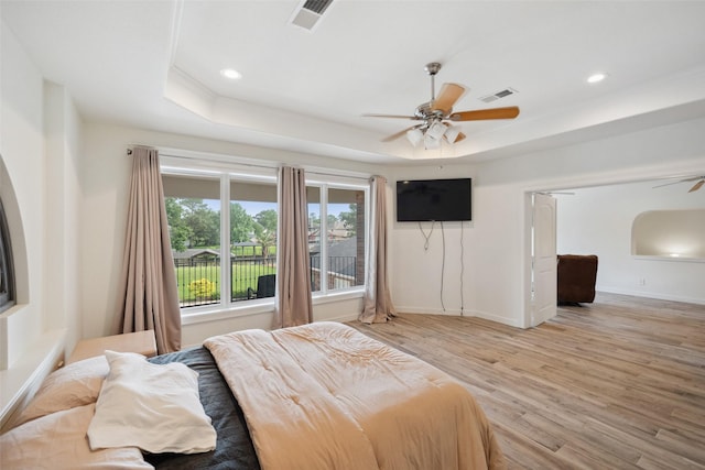 bedroom featuring light wood finished floors, visible vents, and a raised ceiling