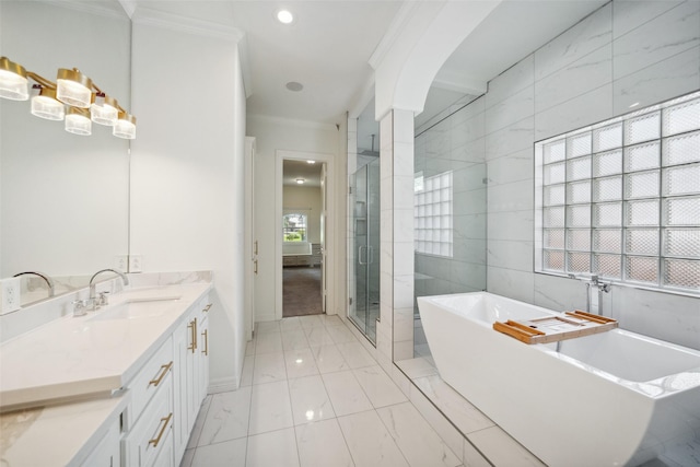 bathroom with vanity, ornamental molding, a stall shower, a freestanding bath, and baseboards