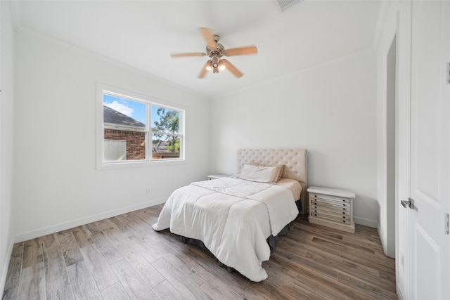 bedroom featuring baseboards, visible vents, crown molding, and wood finished floors