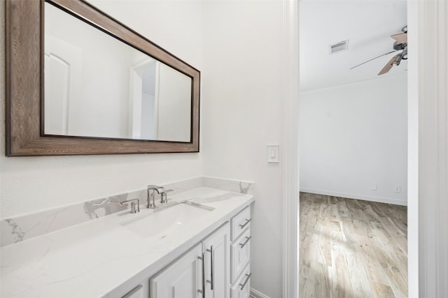 bathroom featuring wood finished floors, vanity, visible vents, a ceiling fan, and baseboards
