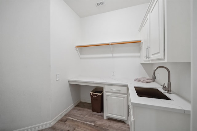 laundry room with light wood finished floors, visible vents, baseboards, and a sink